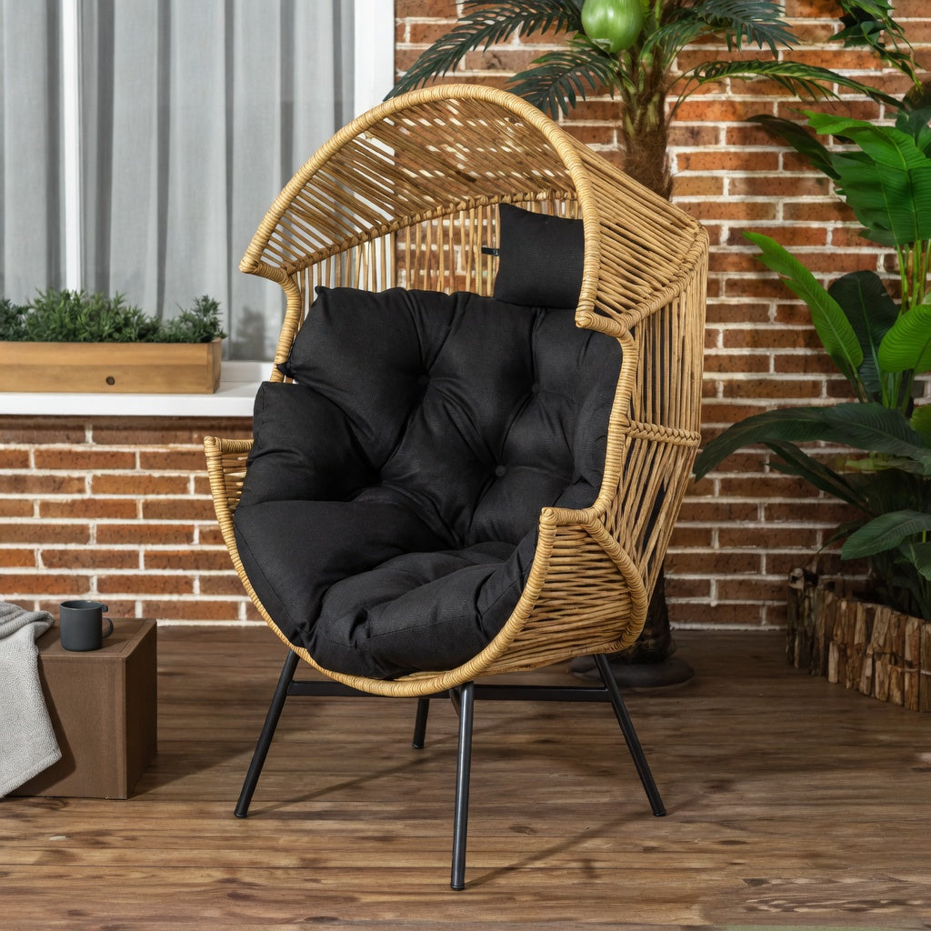 Fauteuil œuf en rotin naturel avec coussins noirs sur une terrasse – RotinDéco