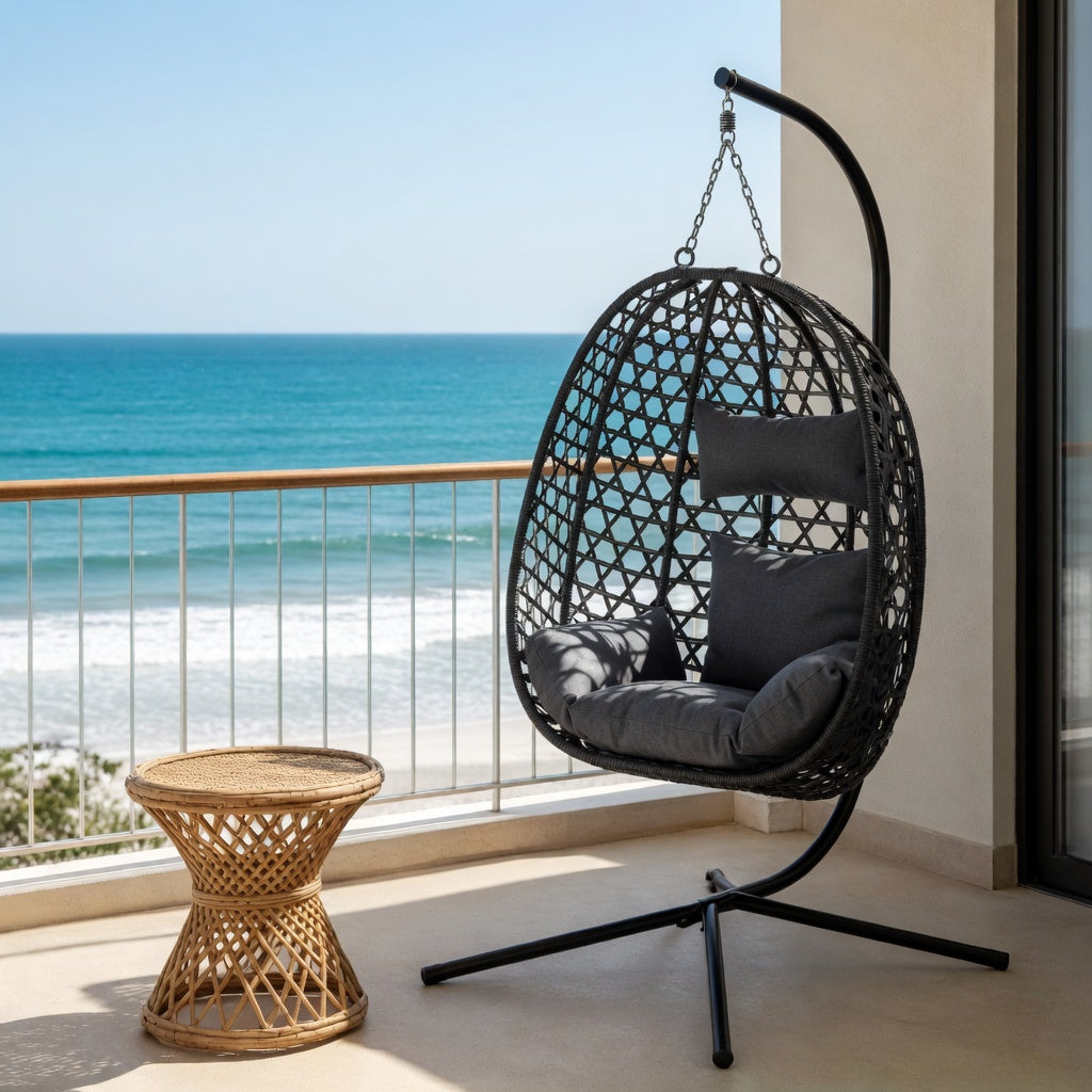 Fauteuil suspendu œuf rotin noir avec coussins gris sur un balcon vue mer – RotinDéco