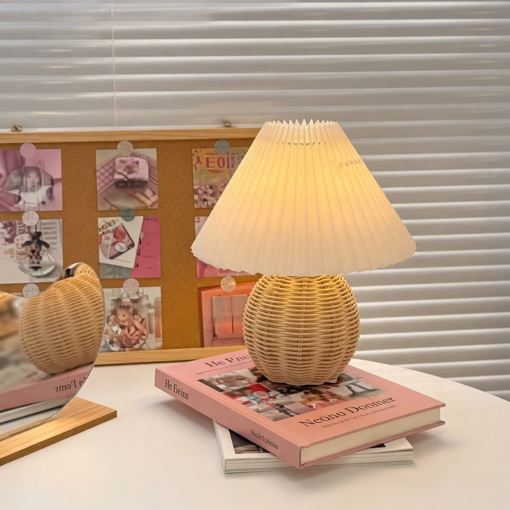 Lampe de chevet rotin tressé abat-jour plissé blanc posée sur des livres sur un bureau
