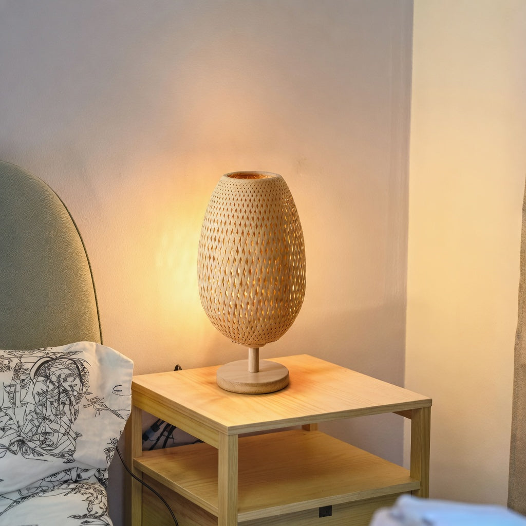 Lampe de table rotin tressé naturel allumée sur table de chevet dans une chambre